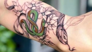 Revisión del tatuaje masculino con serpientes en el brazo.