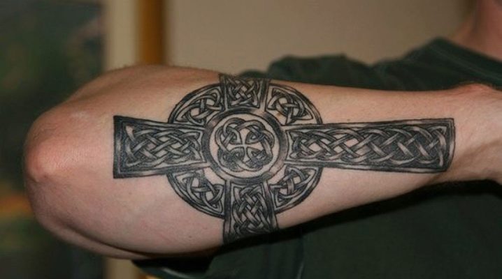 Tatuaje de hombre en forma de cruz en el brazo.